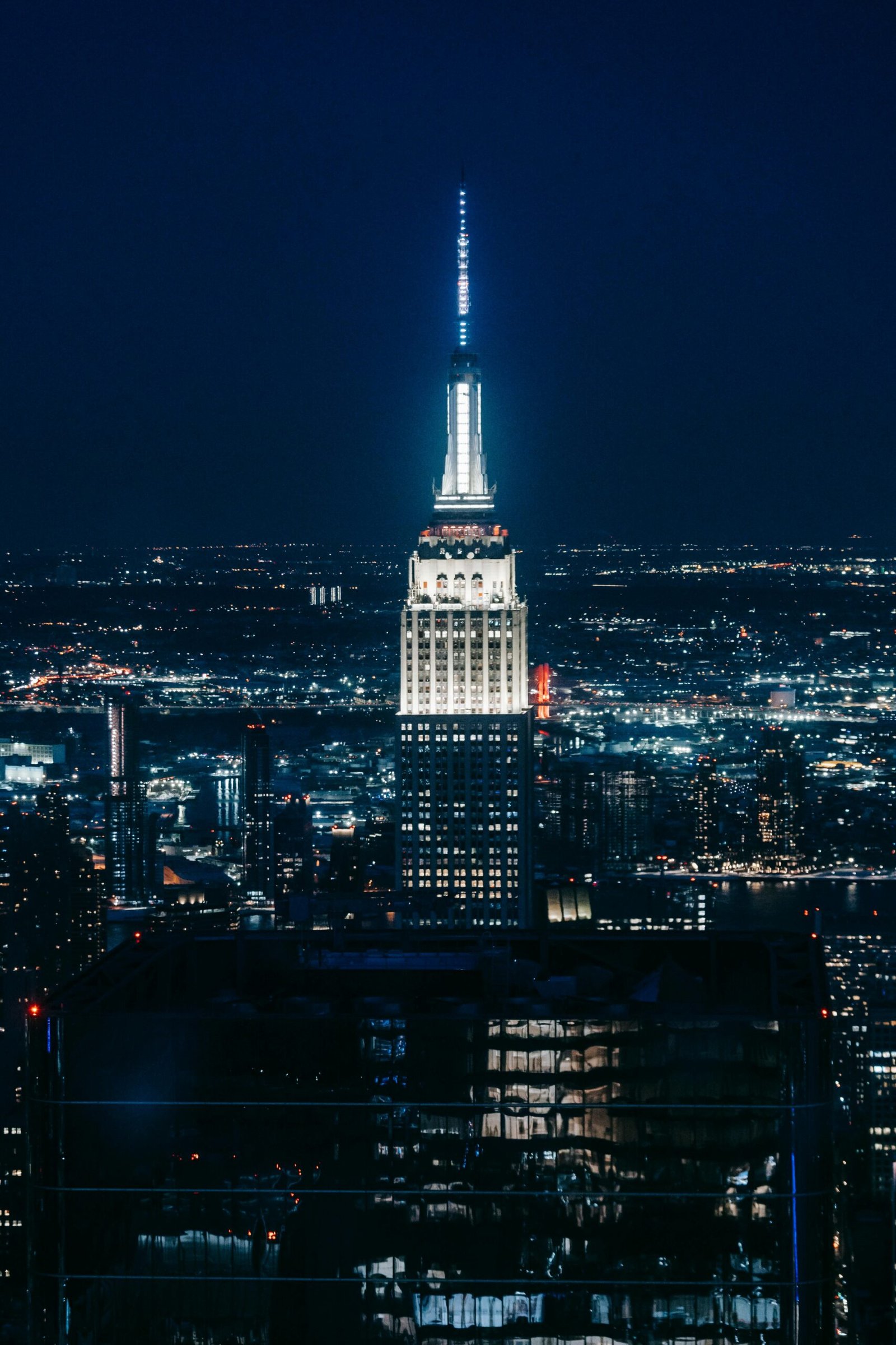 Stunning view of the illuminated Empire State Building amidst New York City skyline at night.